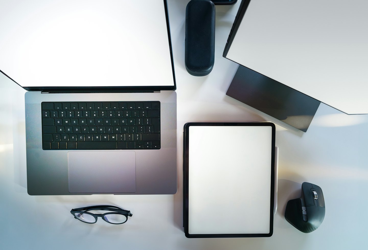 Nowoczesne cyfrowe miejsce pracy z laptopem, tabletem i monitorem na białym biurku.